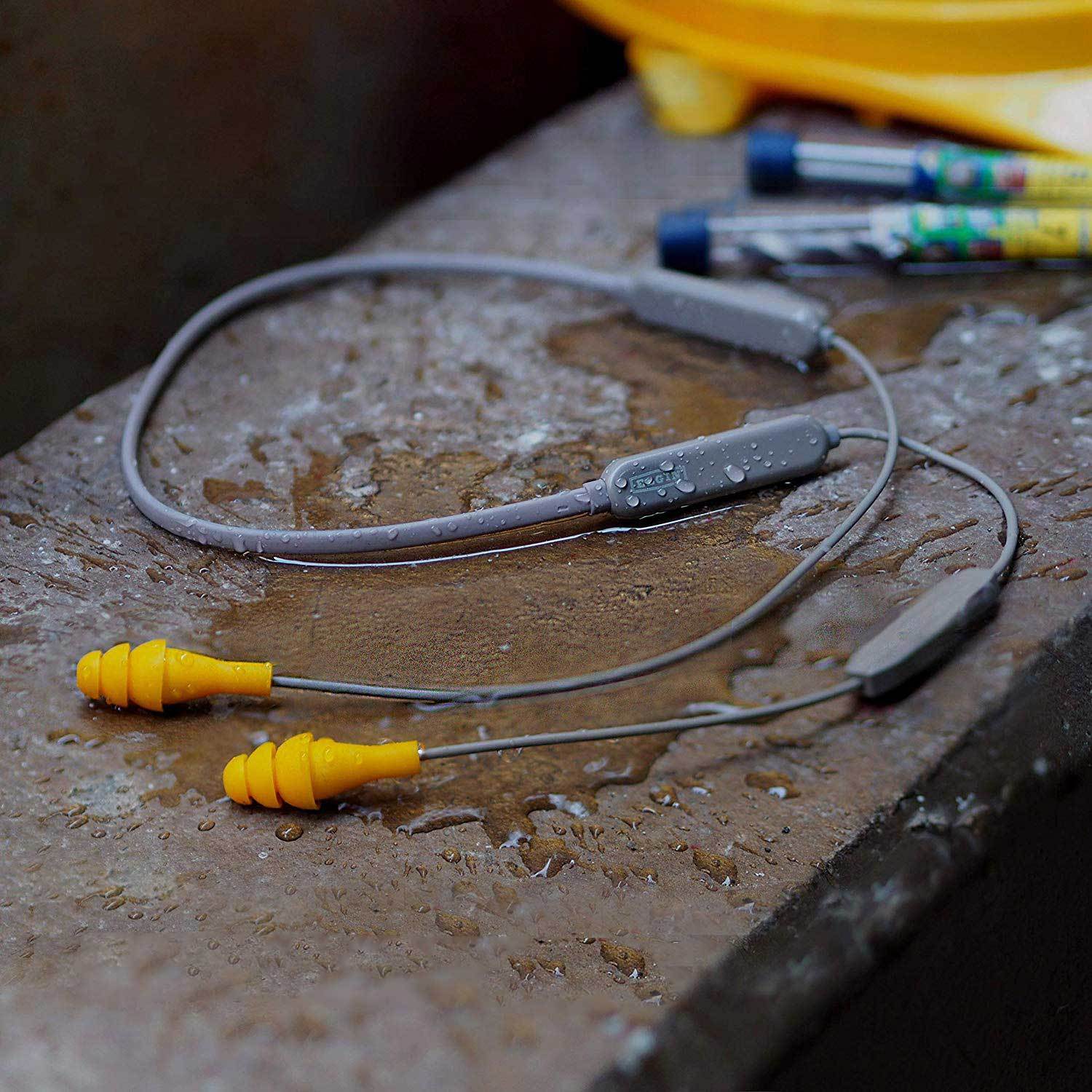 An image of the Elgin® Ruckus Bluetooth Earplug Earbuds laying in water at a construction site.